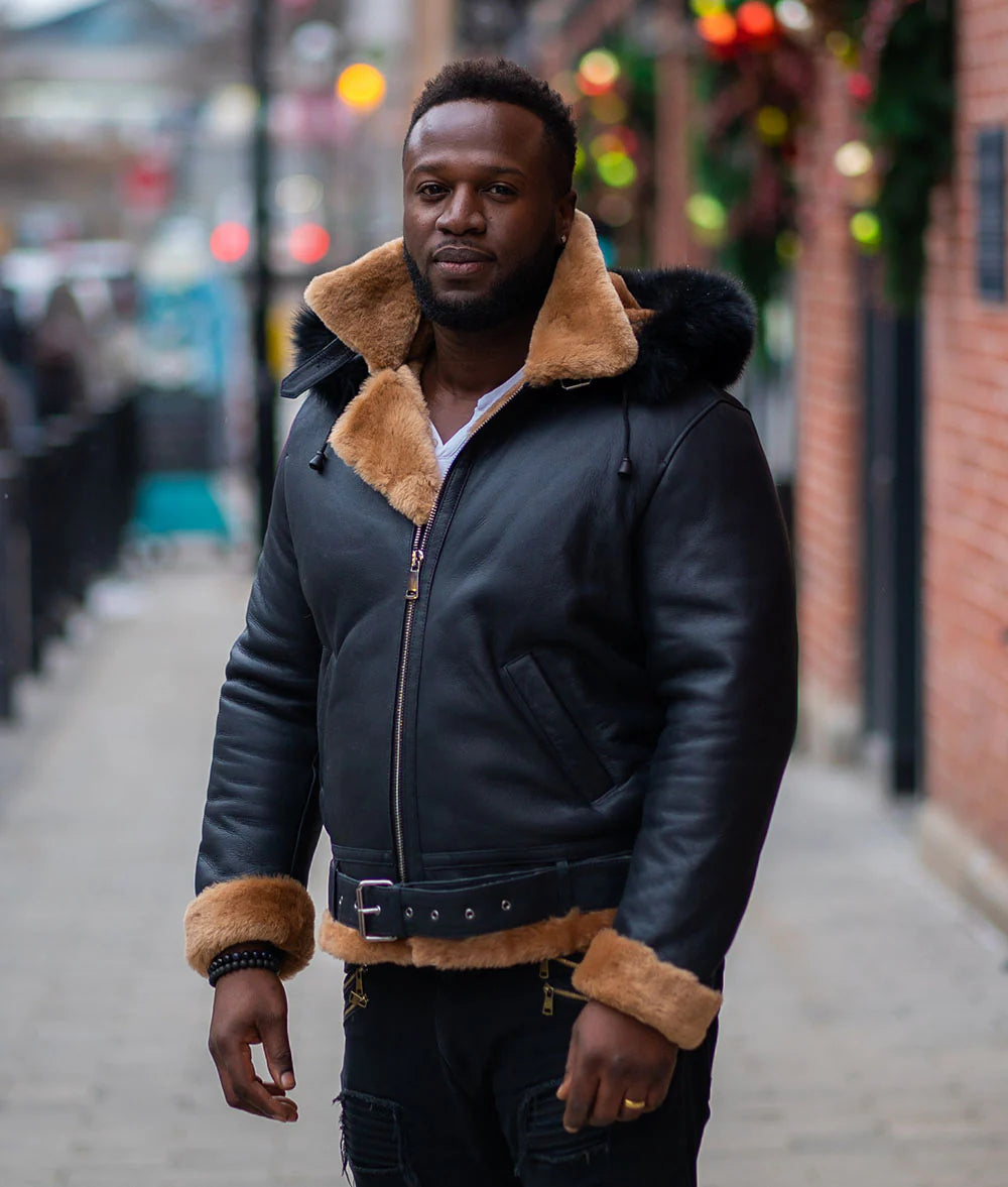 Side view of Jean's B3 Bomber Aviator Shearling Jacket worn by a man with a hoodie on street, highlighting the distressed black leather body and the tan shearling lining. 