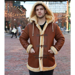 Person wearing a brown leather coat with fur trim in an urban setting.