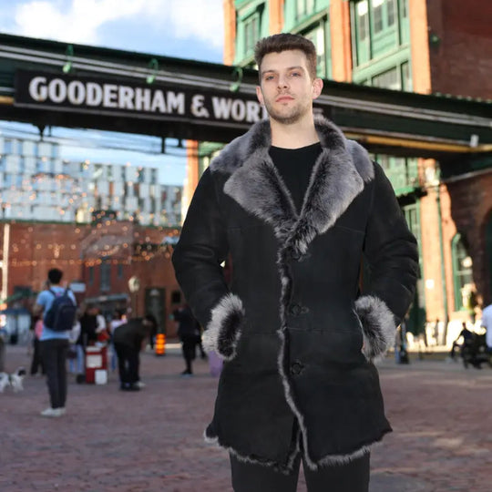 Man wearing a black shearling coat standing in front of a building with 'Gooderham & Worts' sign.
