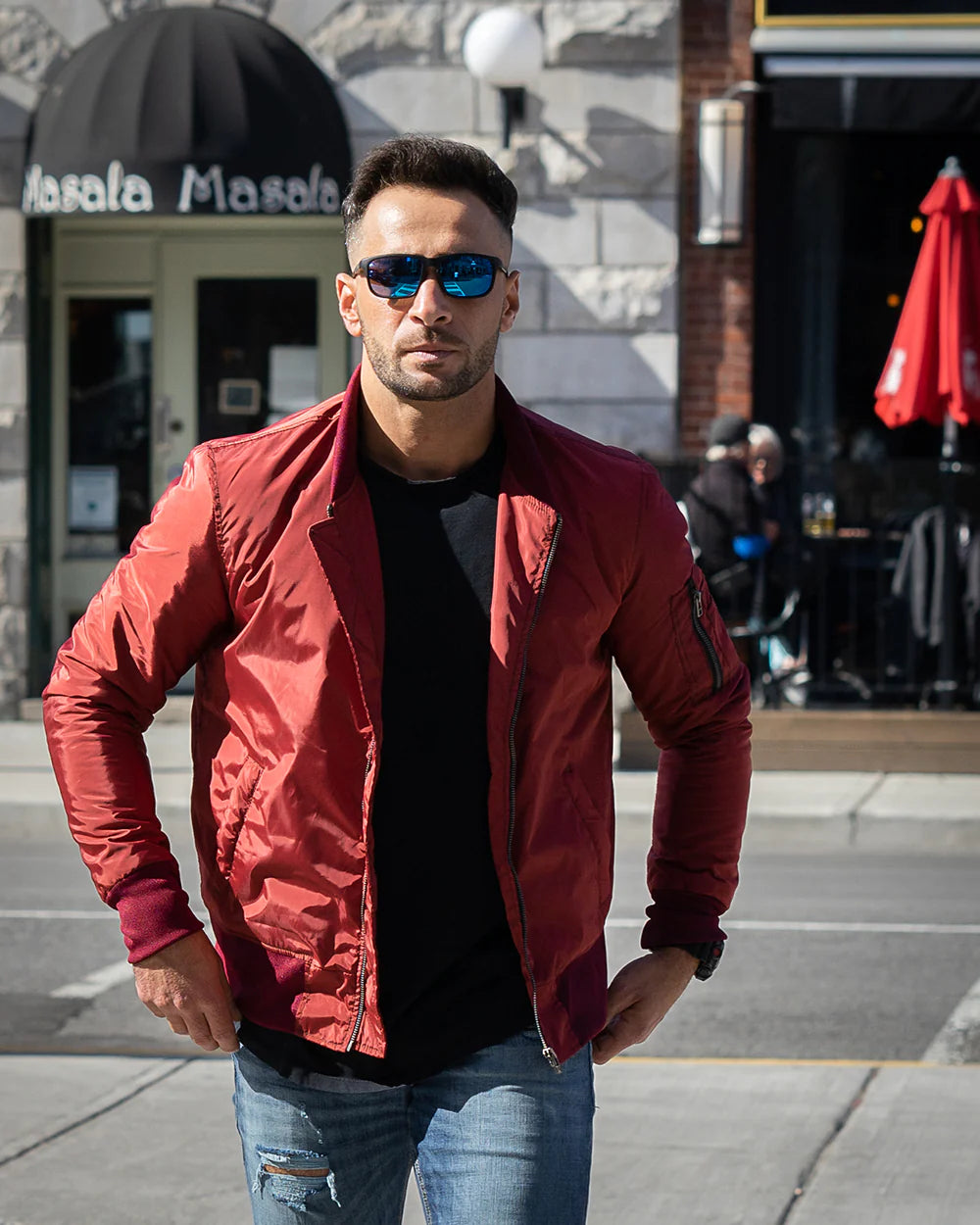 Man wearing a Maroon Nylon Flight Jacket with sunglasses, on a city street.