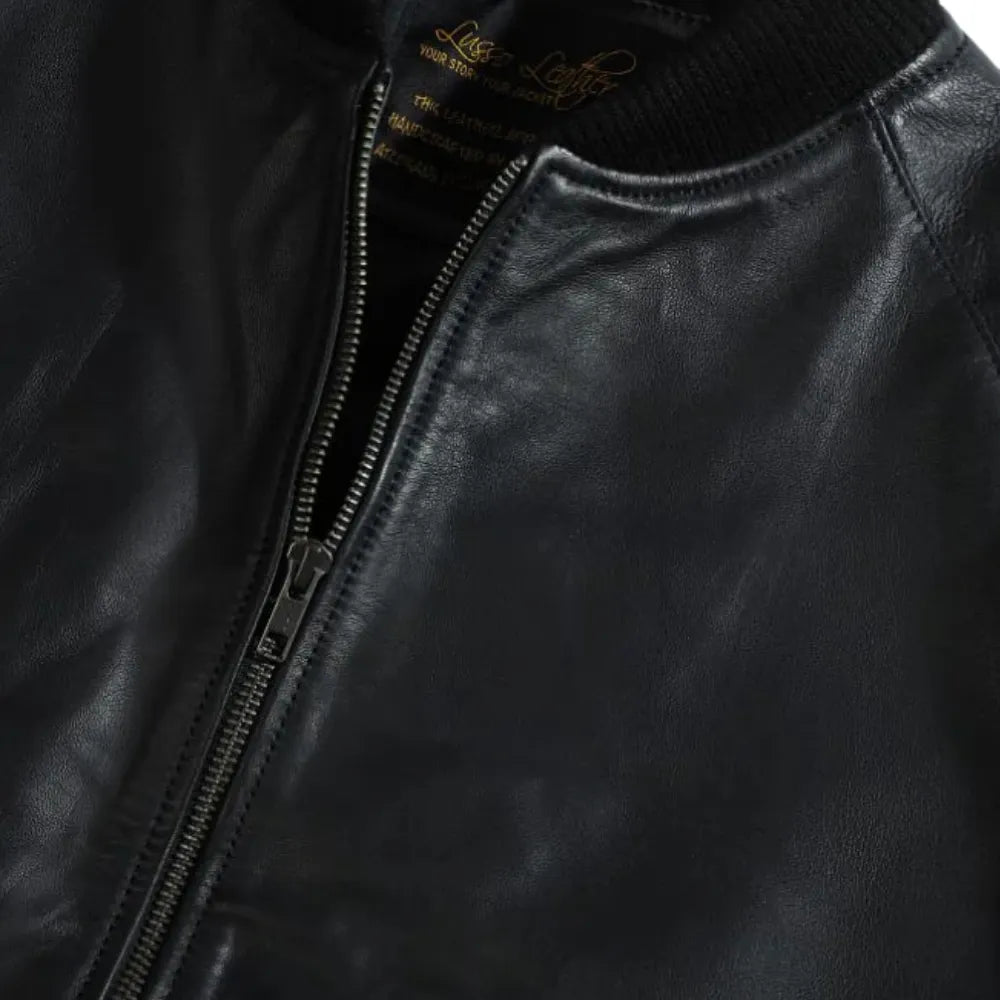Close up of black bomber style leather jacket front zipper and ribbed waistband