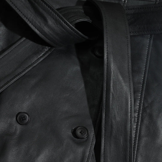 Close-up of a black leather coat with buttons and a strap.