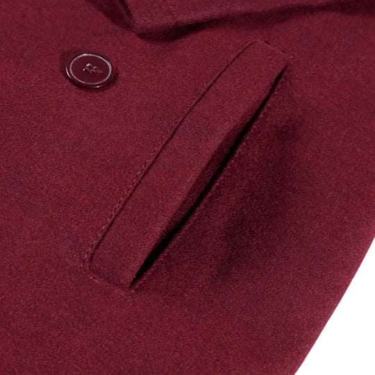Close-up of a burgundy wool overcoat coat pocket with a button on a white background.