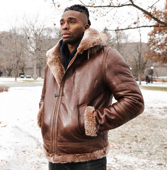 A man posing in the Felix brown hooded bomber jacket, highlighting the durable leather texture and side-entry pockets in a winter setting.