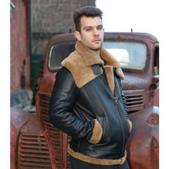 Man wearing Graysen black Aviator bomber shearling jacket with brown fur lining standing in front of an old rusted truck.