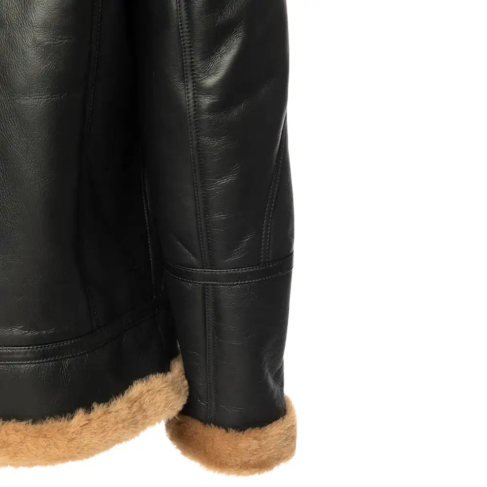 Close-up of the turn-back cuffs of a black Aviator shearling jacket with tan shearling lining.