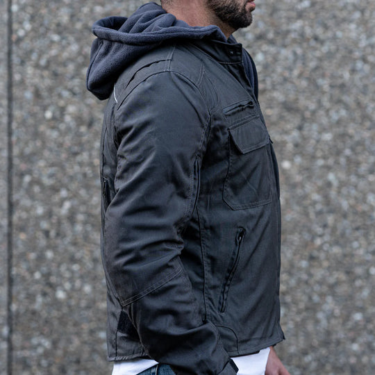 Side view of a model on a motorcycle wearing the grey hooded jacket, demonstrating the relaxed urban fit and the airflow functionality of the vents.