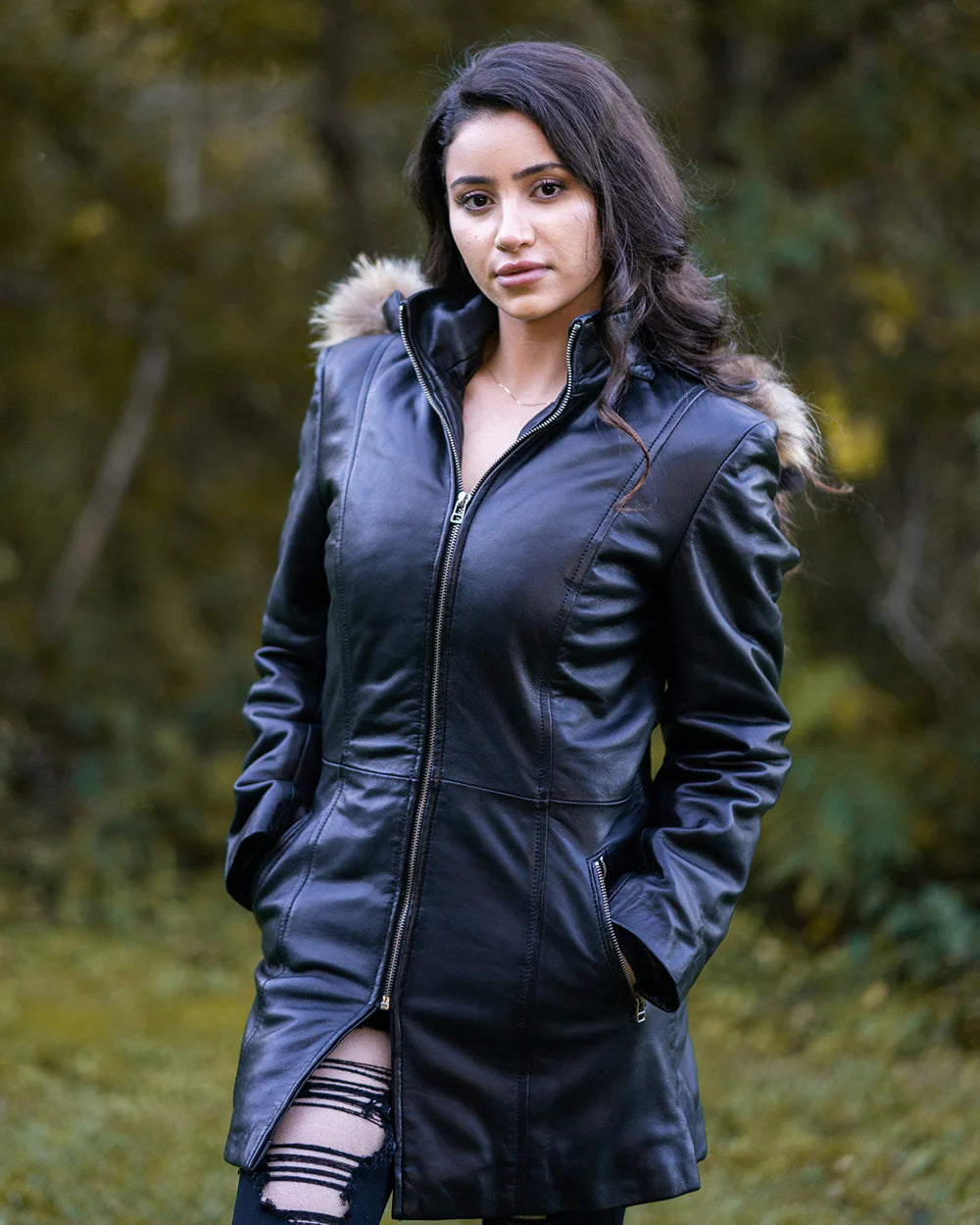 Woman posing in Jazmyn's long winter coat, the protective longline fit in a forest setting.