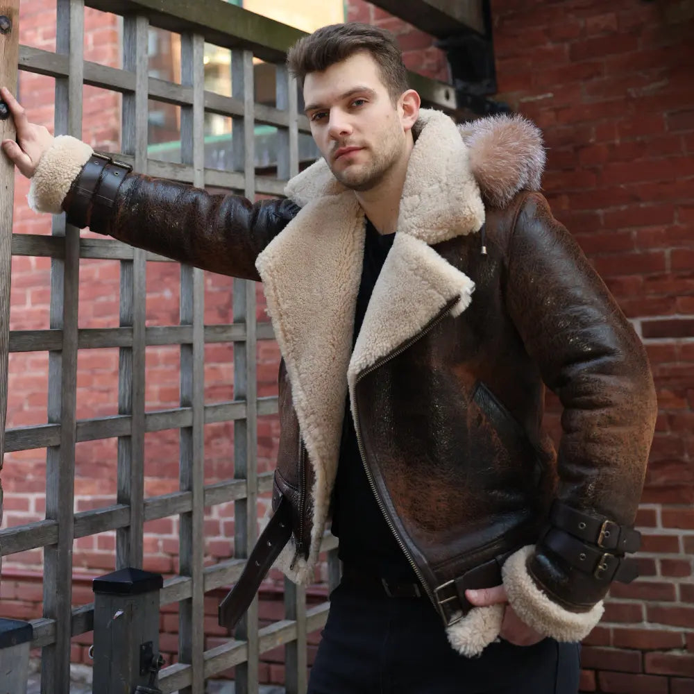 Man wearing Rocco vintage brown aviator shearling jacket with white fur lining against a brick wall.