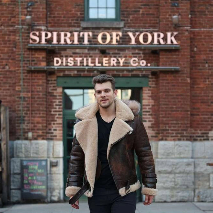 Man wearing Rocco vintage brown aviator shearling jacket in front of the Spirit of York Distillery Co. building.